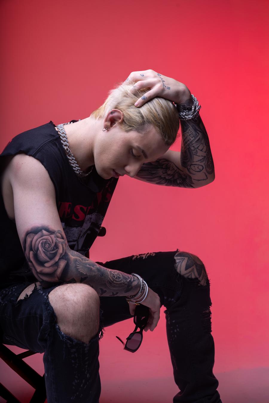 JP Castro com a mão no cabelo, fundo rosa-vermelho